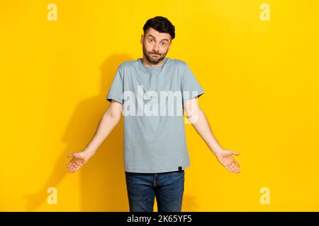 Foto von funky Millennial Brunet Borsten Mann weiß nicht, keine Ahnung Zucken Schultern vergaßen sein Geld nach Hause, bevor Kino auf leuchtend gelbe Farbe isoliert Stockfoto