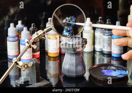 Riesige Lupe, um das Malen von kleinen Figuren von Brettspielen für Rollenspiele verwendet zu erleichtern. Stockfoto