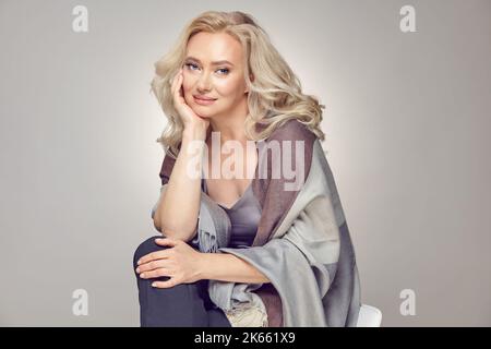 Schöne Frauen im Reifen Alter fühlen sich gut an. Blonde Frau mittleren Alters mit einem tollen Look in stilvoller Freizeitkleidung Stockfoto