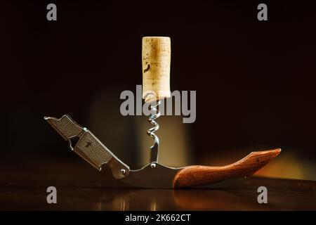 Holzkorken in einem Korkenzieher liegt auf dem Tisch. Flaschenöffner Stockfoto