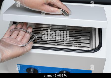 Hand mit Maniküre und Pediküre nach der Sterilisation und Desinfektion von bakteriellen und viralen Infektionen in trockenem Heißluftsterilisator. Stockfoto