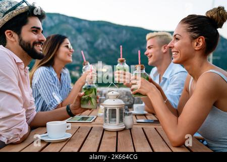 Urlaubsreisen Menschen und Essen Konzept. Glückliche Freunde, die bei der Sommerparty zu Abend essen Stockfoto