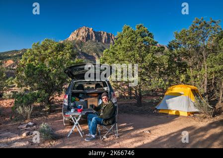 Senior man auf dem Campingplatz, im Wacholderwald von Pinyon, in der Ferne Smithsonian Butte, in der Nähe der Smithsonian Butte Road, Canaan Mountain Wilderness, Utah, USA Stockfoto