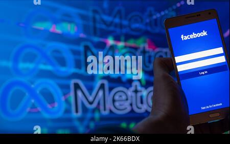 Ein Smartphone mit Facebook-Anmeldebildschirm und Meta-Logo im Hintergrund. Stockfoto