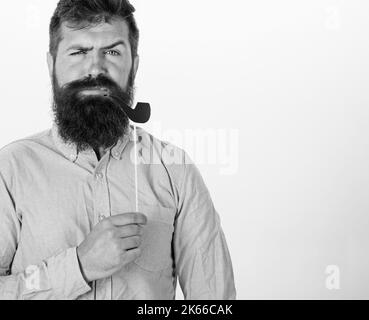 Guy raucht Tabakpfeife. Hipster mit Bart und Schnurrbart auf ernstem Gesicht posiert mit Fotokabine Requisiten, Kopierraum. Alte Gewohnheiten Konzept. Mann hält Stockfoto