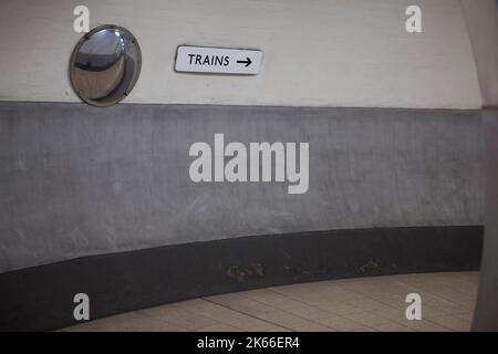 Ein Schild mit der Aufschrift „ZÜGE“ mit einem Pfeil, der nach rechts in einem Tunnel in der U-Bahn an der Station Holland Park der Central Line im Westen Londons zeigt Stockfoto