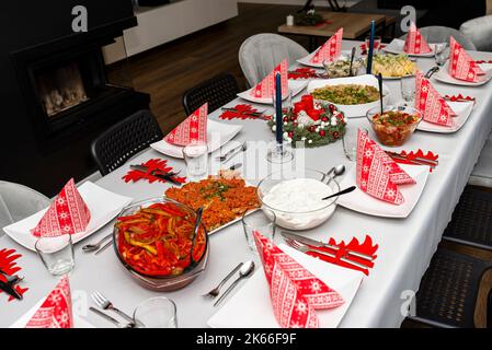 Ein Tisch vor dem Abendessen zu Weihnachten in Polen, sichtbare gebackene Fischfilets in Karottensalat und Spinatroulade. Stockfoto