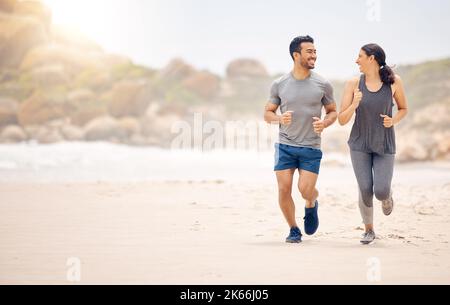 Beach Running ist eine hervorragende Möglichkeit, Ihre Herz-Kreislauf-Fitness zu steigern. Ein sportliches junges Paar, das gemeinsam am Strand läuft. Stockfoto