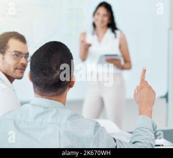 ID möchte eine Frage stellen, bevor Sie fortfahren. Rückansicht eines Geschäftsmannes, der seine Hand während einer Besprechung in einem Büro hob. Stockfoto