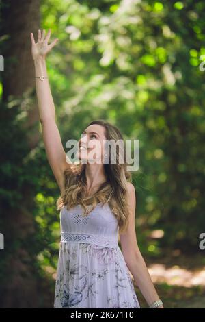 Schöne fröhliche junge Frau mit dunkelgrünen launischen Hintergrund in der Natur Stockfoto