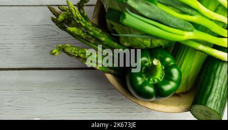 Blick von oben auf frischen Spargel, grüne Paprika, Gurke, chinakohl in der Schüssel auf dem Tisch Stockfoto