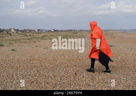 Ein Mann, der als Migranten gedacht wurde, geht über den Dungeness Strand, nachdem er vom Dungeness Rettungsboot nach einem Vorfall mit einem kleinen Boot im Kanal gebracht wurde. Bilddatum: Mittwoch, 12. Oktober 2022. Stockfoto