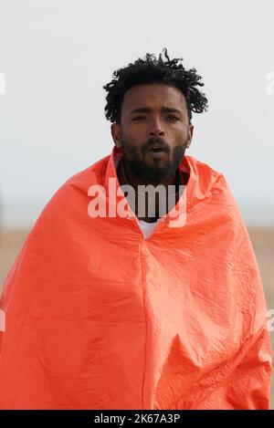 Ein Mann, der als Migrant gedacht wird, läuft über den Dungeness-Strand, nachdem er nach einem Vorfall mit einem kleinen Boot im Kanal vom Dungeness-Rettungsboot gebracht wurde. Bilddatum: Mittwoch, 12. Oktober 2022. Stockfoto