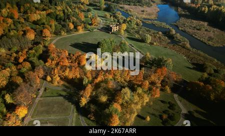 Herbstlicher Stadtpark. Bäume mit bunten Blättern. Sportplätze und der Fluss. Herbstlandschaft. Luftaufnahmen. Stockfoto