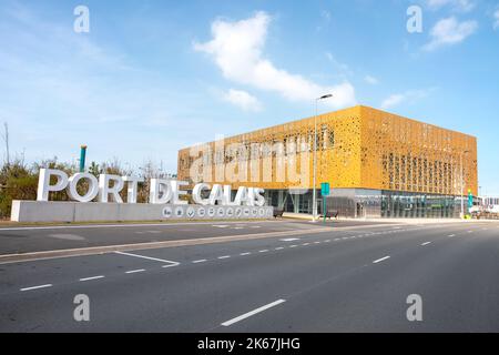 Das Gebäude von Port De Calais. Die leuchtend gelbe Architektur leuchtet unter einem leuchtend blauen Himmel neben der großen Steinbeschilderung. 11.. September 22 Stockfoto