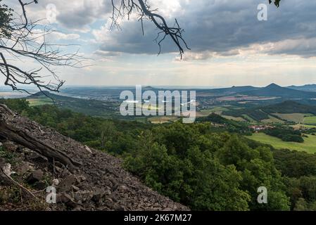 Blick vom Plesivec-Hügel in den Ceske stredohori-Bergen in Tschechien während des Sommernachmittags mit blauem Himmel und Wolken Stockfoto