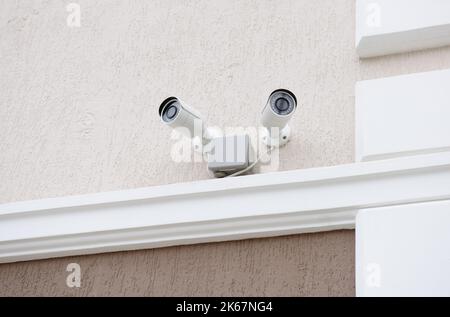 Zwei CCTV-Überwachungskameras an der Wand der Fassade des Hauses. Stockfoto