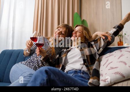 Betrunkene Mutter und Tochter entspannen sich auf der Couch und trinken Rotwein Stockfoto
