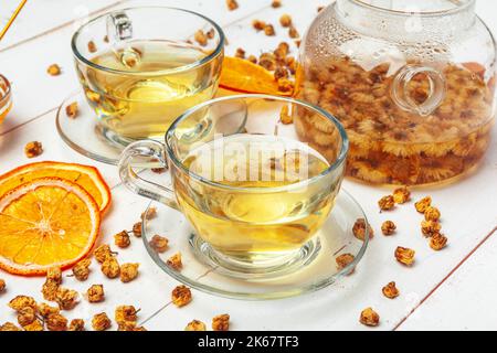 Glaskessel und Tasse Kräutertee auf weißem Holzhintergrund Stockfoto