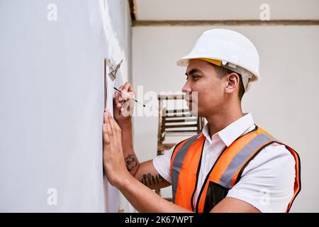 Ein Bauleiter überprüft das Renovierungsprojekt mit einer Checkliste auf der Zwischenablage Stockfoto