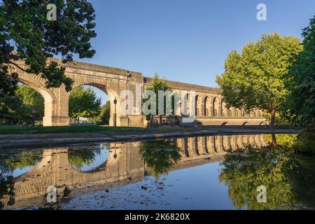 Landschaftsansicht von St Clement aka Arceaux Aquädukt antikes Steingebäude mit Reflexion im Pool im Garten der Promenade du Peyrou, Montpellier, Frankreich Stockfoto