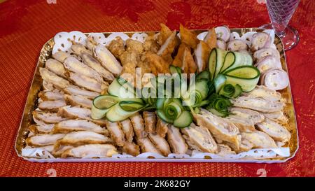 Ein Teller mit köstlichem gewürztem Hühnerfleisch, verziert mit Scheiben frischer Gurken Stockfoto