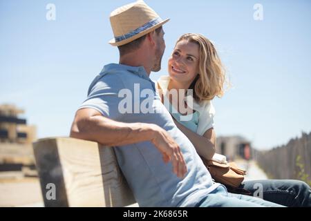 Freunde sitzen auf einer Bank reden und Spaß haben Stockfoto