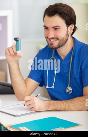 Junger männlicher Arzt, der Informationen über die Verwendung von Inhalator gibt Stockfoto