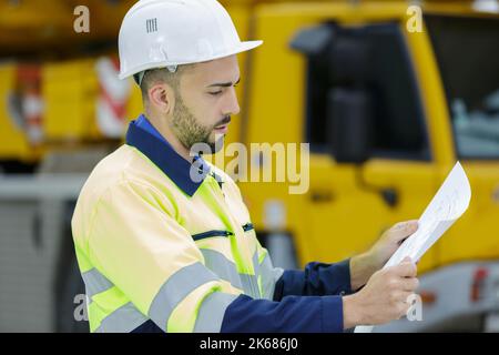 Mechaniker, der ein Klemmbrett vor einem Auto hält Stockfoto