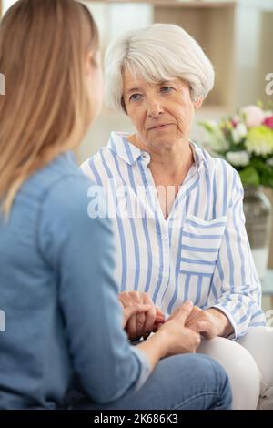 Traurige ältere und junge Frau, die zu Hause spricht Stockfoto