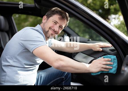 Glücklicher Mann putzt im Auto Stockfoto