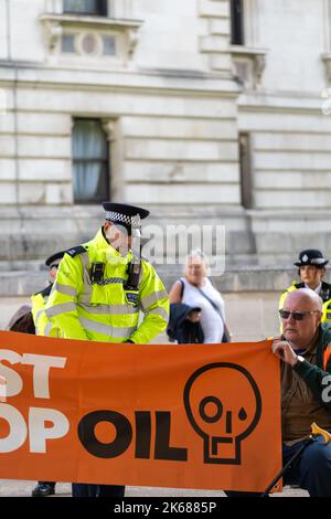 Zwei „Just Stop Oil“-Anhänger kletterten am Mittwoch (12. Oktober) inmitten eines fortlaufenden Wagens auf einen Metropolitan Police Van vor der Horse Guards Road in London Stockfoto