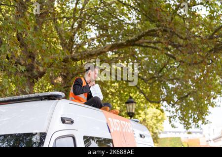 Zwei „Just Stop Oil“-Anhänger kletterten am Mittwoch (12. Oktober) inmitten eines fortlaufenden Wagens auf einen Metropolitan Police Van vor der Horse Guards Road in London Stockfoto