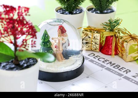 Countdown zu Weihnachten, festliche Schneekugel und andere Dekorationen auf Dezember Kalender, Kiefer, Weihnachtsgeschenke, Glocke Stockfoto