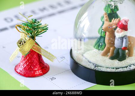 Weihnachten Schneekugel und glänzend rote Glocke markieren Weihnachten, 25. Dezember, auf dem Kalender Stockfoto