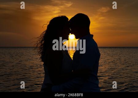 Junges, liebevolles Paar bei Sonnenuntergang in der Karibik. Stockfoto
