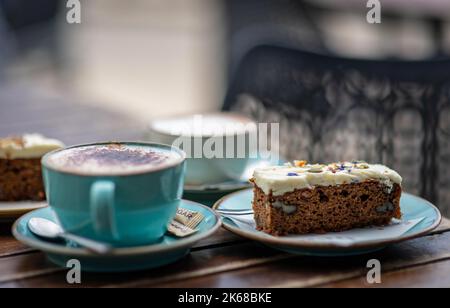 Kaffee und Karottenkuchen für zwei auf einem Tisch vor einem Café in St. Ives Stockfoto