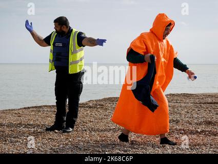 Ein Mann, der als Migranten gedacht wurde, geht über den Dungeness Strand, nachdem er vom Dungeness Rettungsboot nach einem Vorfall mit einem kleinen Boot im Kanal gebracht wurde. Bilddatum: Mittwoch, 12. Oktober 2022. Stockfoto