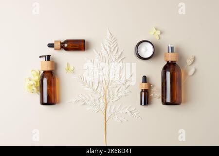 Kosmetische Komposition mit kosmetischen Hautpflegeprodukten und Blumen auf pastellbeigem Hintergrund. Flach liegend, Kopierplatz Stockfoto