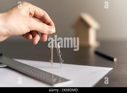 Architekt zeichnet mit dem Kompass auf ein weißes Papier die Pläne für ein neues Zuhause für eine Familie. Stockfoto