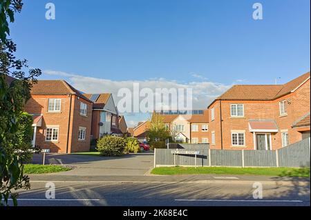 Moderne britische Häuser in einer Sackgasse in einem Stadtvorort mit blauem Himmel Stockfoto