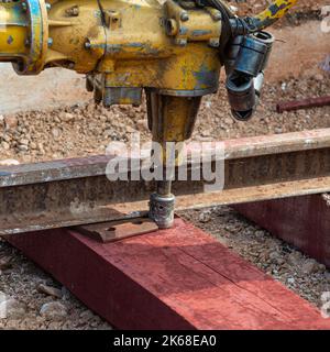 Bahnarbeiter, die die Gleisschiene verschrauben. Detailarbeiter mit mechanischem Schraubenschlüssel Stockfoto