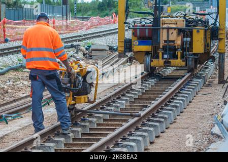 Bahnarbeiter, die die Gleisschiene verschrauben. Detailarbeiter mit mechanischem Schraubenschlüssel Stockfoto