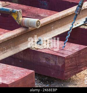 Bahnarbeiter, die die Gleisschiene verschrauben. Detailarbeiter mit leichter tragbarer Schlaffenbohrmaschine Stockfoto