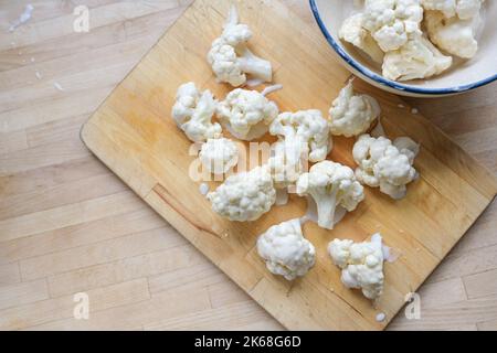 Blumenkohlröschen, mit Teig auf einem Holzschneidebrett als Vorbereitung zum Braten überzogen, vegetarisches Kochen mit Gemüse, Kopierraum, hoher Winkel Stockfoto