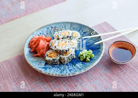 Sushi-Rolle mit Avocado, Frischkäse, Sesam. Sushi-Menü. Japanische Küche Uramaki-Brötchen mit geräuchertem Fisch und frischem Gemüse Stockfoto