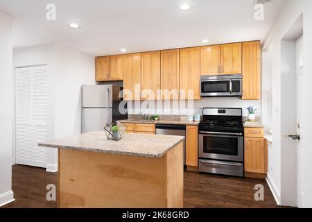 Eine Küche mit Holzschränken, Marmorablagefläche und Geräten aus Edelstahl. Stockfoto