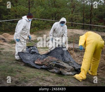 Lyman, Ukraine. 11. Oktober 2022. (ANMERKUNG DES HERAUSGEBERS: Bilder zeigen den Tod) Ermittler, die Schutzkleidung tragen, werden gesehen, wie sie die Leichen ukrainischer Soldaten von einer Grabstätte in Lyman exhumieren. Mindestens 32 ukrainische Soldatenleichen wurden aus einem Massengrab in Lyman, einer Stadt im Donezker Gebiet, die unter russischer Besatzung stand, exhumiert. Die Behörden sagten, dass sie zusammen begraben wurden und erste Untersuchungen zeigten, dass einige Leichen mit verbundenen Augen und an den Händen gebunden waren, was Anzeichen von Folter und Hinrichtung nahelegt. Weitere 22 Zivilisten, darunter auch Kinder, wurden von einer anderen Begräbnisstätte in der Nähe exhumiert. B Stockfoto