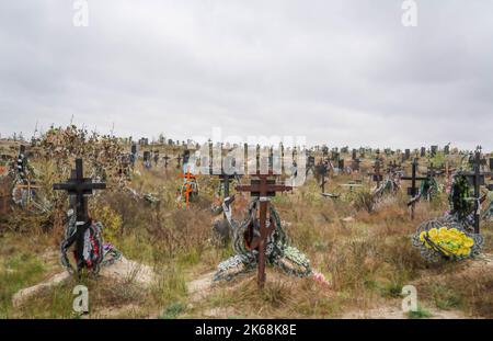 Lyman, Ukraine. 11. Oktober 2022. Der Friedhof neben einer Grabstätte, die von den Ukrainern entdeckt wurde, nachdem die Stadt von russischen Truppen im Donezker Gebiet befreit wurde. Mindestens 32 ukrainische Soldatenleichen wurden aus einem Massengrab in Lyman, einer Stadt im Donezker Gebiet, die unter russischer Besatzung stand, exhumiert. Die Behörden sagten, dass sie zusammen begraben wurden und erste Untersuchungen zeigten, dass einige Leichen mit verbundenen Augen und an den Händen gebunden waren, was Anzeichen von Folter und Hinrichtung nahelegt. Weitere 22 Zivilisten, darunter auch Kinder, wurden von einer anderen Begräbnisstätte in der Nähe exhumiert. Beide Standorte l Stockfoto