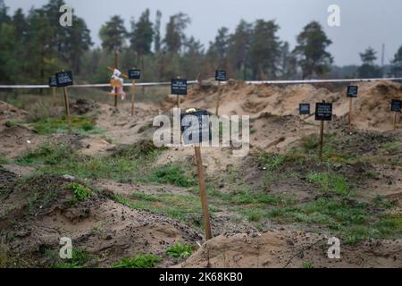 Lyman, Ukraine. 11. Oktober 2022. Auf einer Grabstätte in Lyman ist eine Tafel mit Datum und Namen zu sehen. Die Ermittler sagten, dass hauptsächlich Zivilisten an diesem Ort begraben wurden. Mindestens 32 ukrainische Soldatenleichen wurden aus einem Massengrab in Lyman, einer Stadt im Donezker Gebiet, die unter russischer Besatzung stand, exhumiert. Die Behörden sagten, dass sie zusammen begraben wurden und erste Untersuchungen zeigten, dass einige Leichen mit verbundenen Augen und an den Händen gebunden waren, was Anzeichen von Folter und Hinrichtung nahelegt. Weitere 22 Zivilisten, darunter auch Kinder, wurden von einer anderen Begräbnisstätte in der Nähe exhumiert. Beide Standorte befinden sich in einem Stockfoto